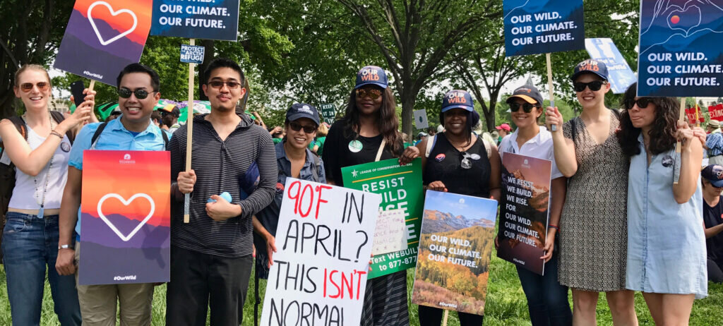 Group of people standing together holding up climate change signs