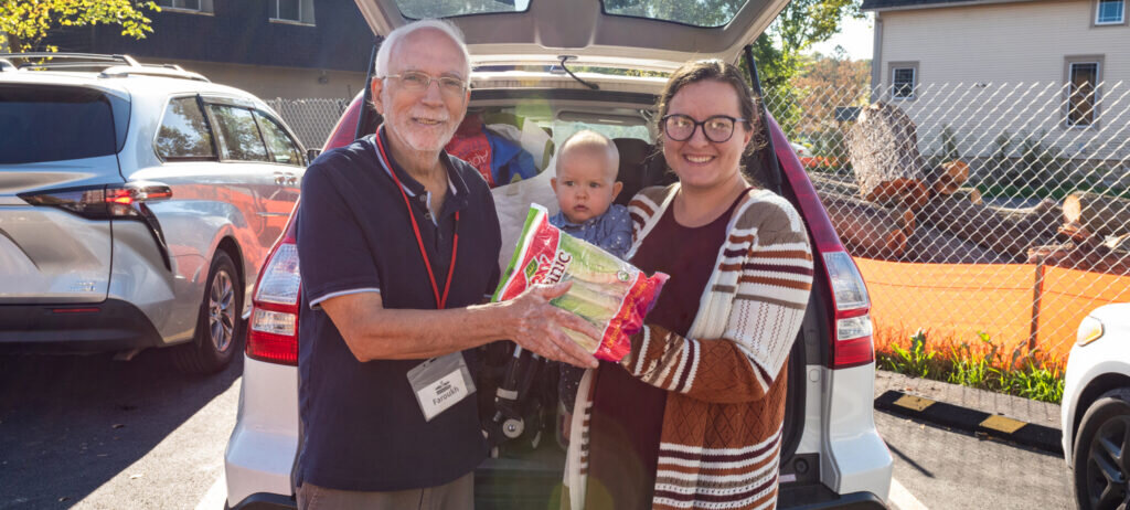 A volunteer hands lettuce to a neighbor as part of PRC’s Food Pantry program. PRC’s Food Pantry offers a variety of quality food and connects clients with other PRC services and resources.
