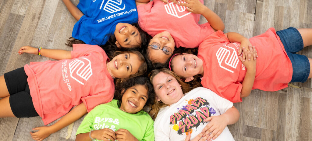 Group of young girls laying on the floor smiling