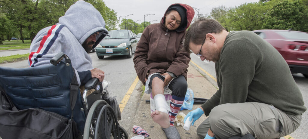 Man treating an unsheltered resident on the street