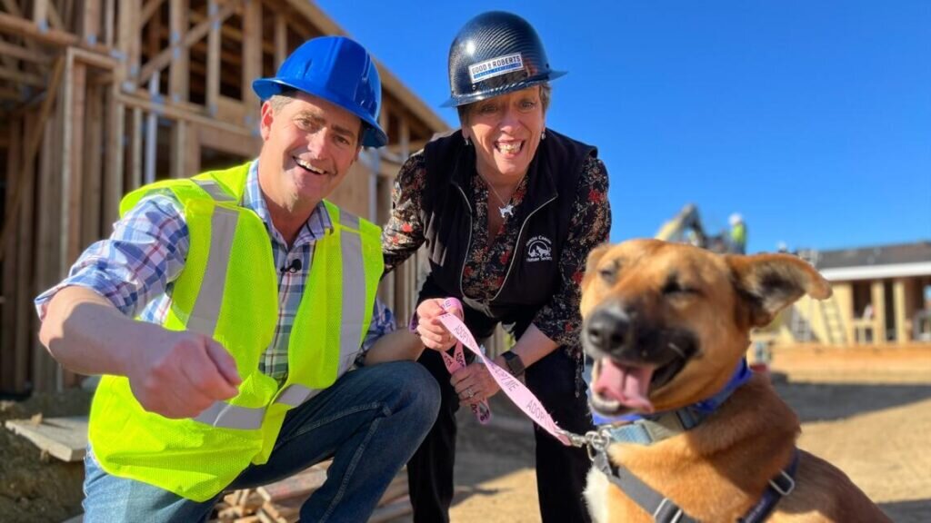 Two people interact with their dog at a construction site