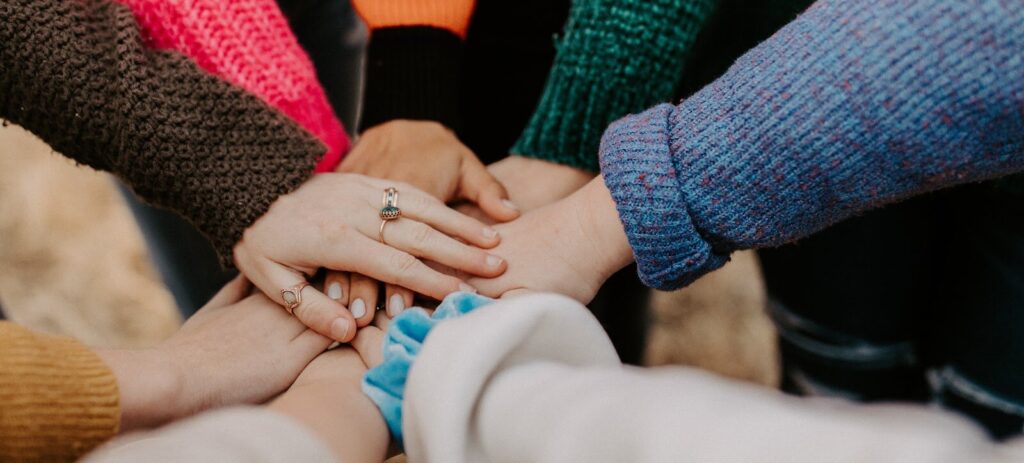 several people's hands overlap in a circle