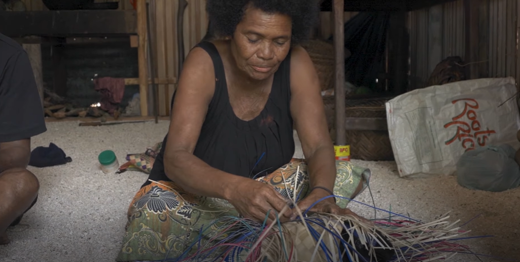 Woman sitting on floor weaving