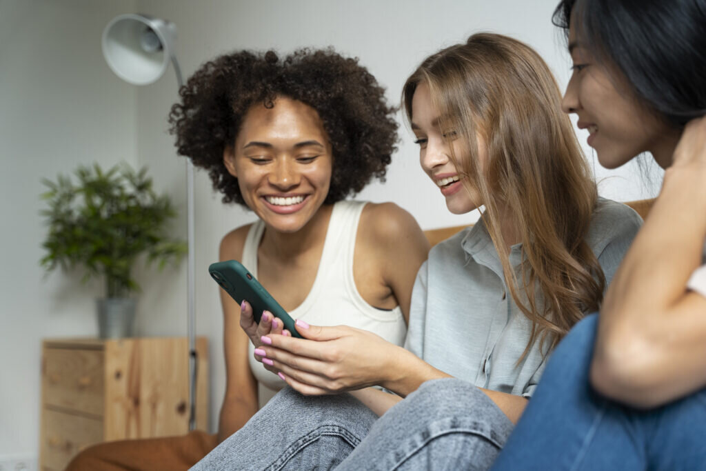 Three girls looking at a phone laughing
