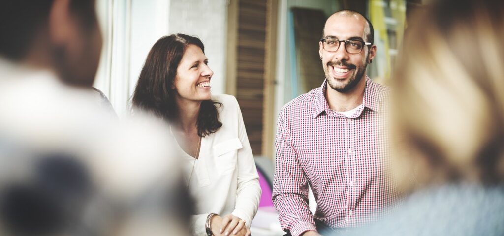 Two professionals speaking at a meeting and smiling