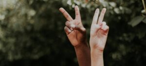Two nonprofit professionals holding allyship peace signs