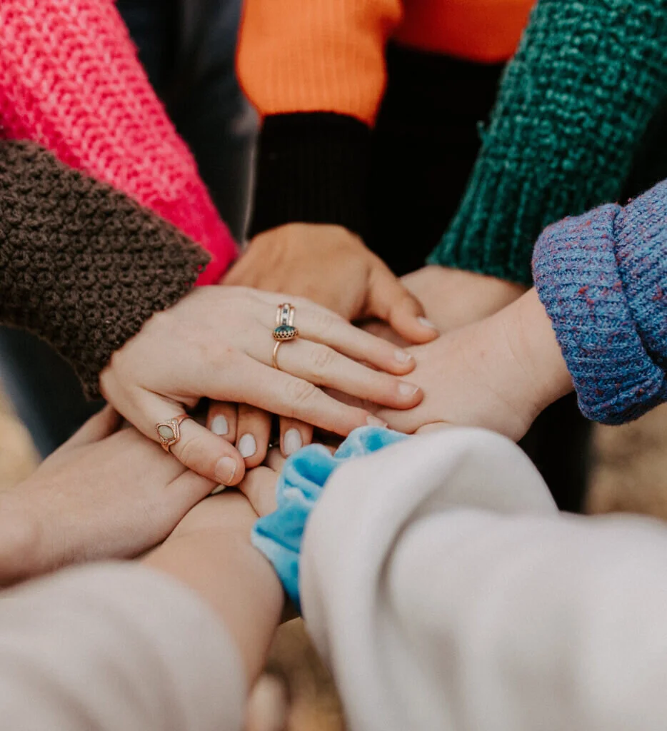 several people's hands overlap in a circle